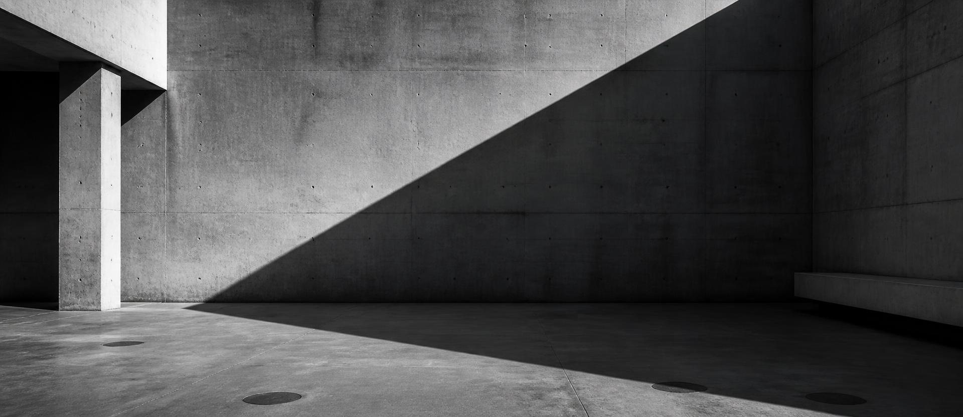 Empty brutalist concrete courtyard with diagonal light